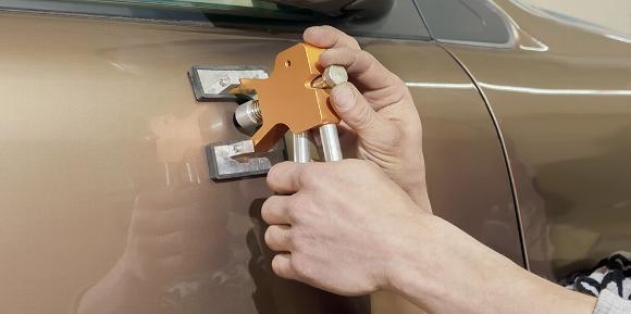 Mechanic performing a paintless dent removal on car door