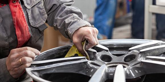 Mechanic refurbishing car tyre alloys
